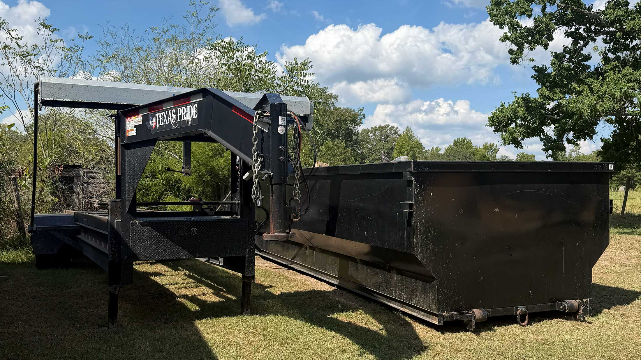 Roll-off dumpster and delivery trailer used by C3 Rentals in East Texas
